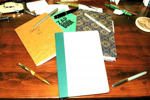 Notebooks and pens on a wooden desk.