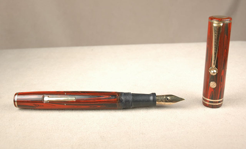 Vintage red fountain pen with cap detached.