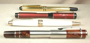 Four assorted pens on a white surface.