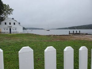 White fence by a lake with boathouse.