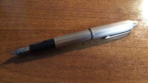 Silver fountain pen on wooden surface.