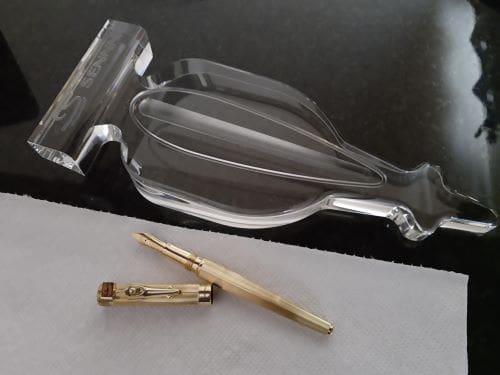 Gold pen and clear glass award trophy.