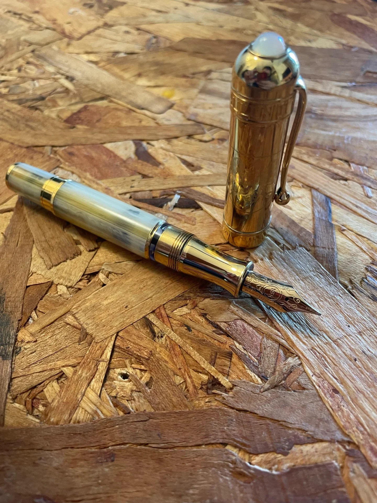 Gold fountain pen on wooden surface.